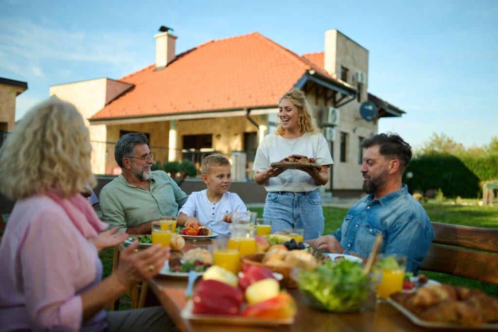 Familie beim Essen im Garten mit Blick aufs Haus