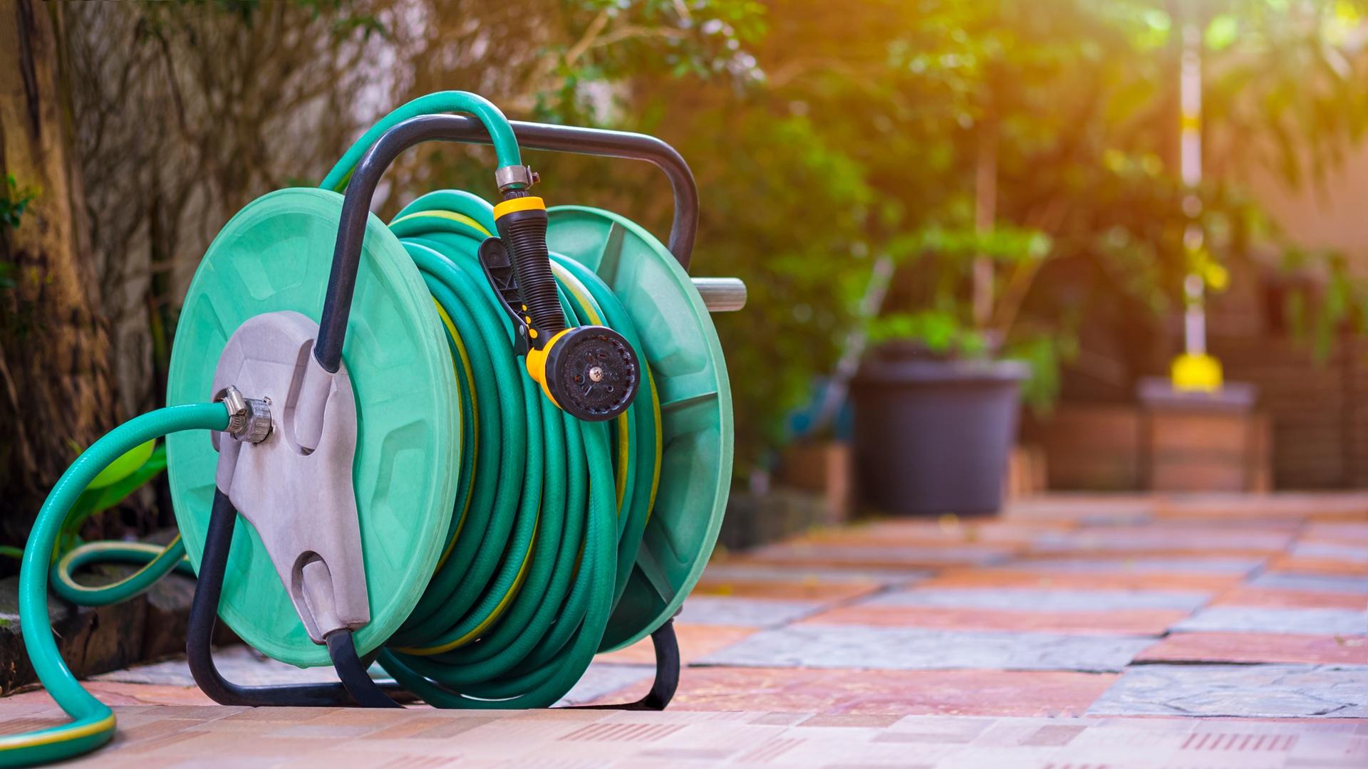 Grüner Gartenschlauch auf Rolle steht bereit für die Bewässerung | Poolschlauch